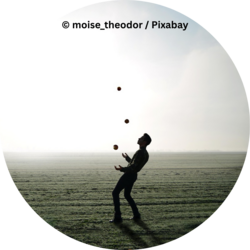 Person jongliert mit drei Bällen auf einem weiten, nebligen Feld im Gegenlicht.