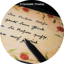 Nahaufnahme eines handgeschriebenen Textes auf cremefarbenem Papier mit Blumenmuster; im Vordergrund liegt die Spitze eines schwarzen Füllers.