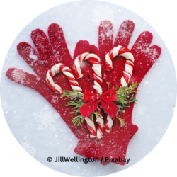 Rote Winterhandschuhe liegen im Schnee, darauf drei Zuckerstangen mit Tannenzweigen und roter Schleife.