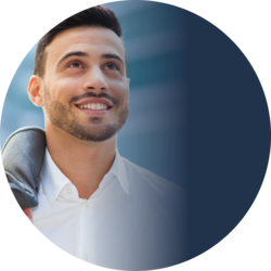 Junger Mann mit Bart lächelt und blickt nach oben; er trägt ein weißes Hemd und hat ein Jackett über die Schulter gelegt.