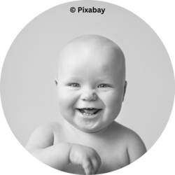 Lachendes Baby in Schwarz-Weiß-Porträtaufnahme vor hellem Hintergrund.