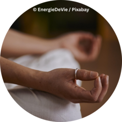 Person sitzt im Schneidersitz und hält die Hände in einer Meditationshaltung, mit Daumen und Zeigefinger zusammengelegt.