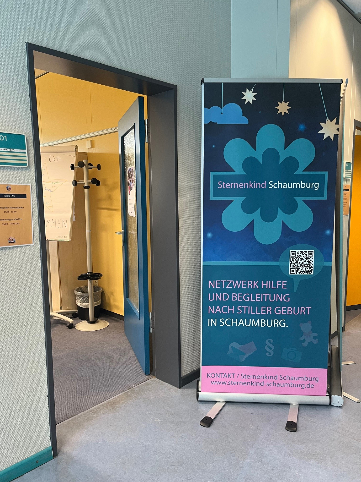 Ein Aufsteller von Sternenkind Schaumburg informiert über Hilfe und Begleitung nach einer stillen Geburt. Daneben befindet sich der Raum für das Angebot zum Thema Sternenkinder.