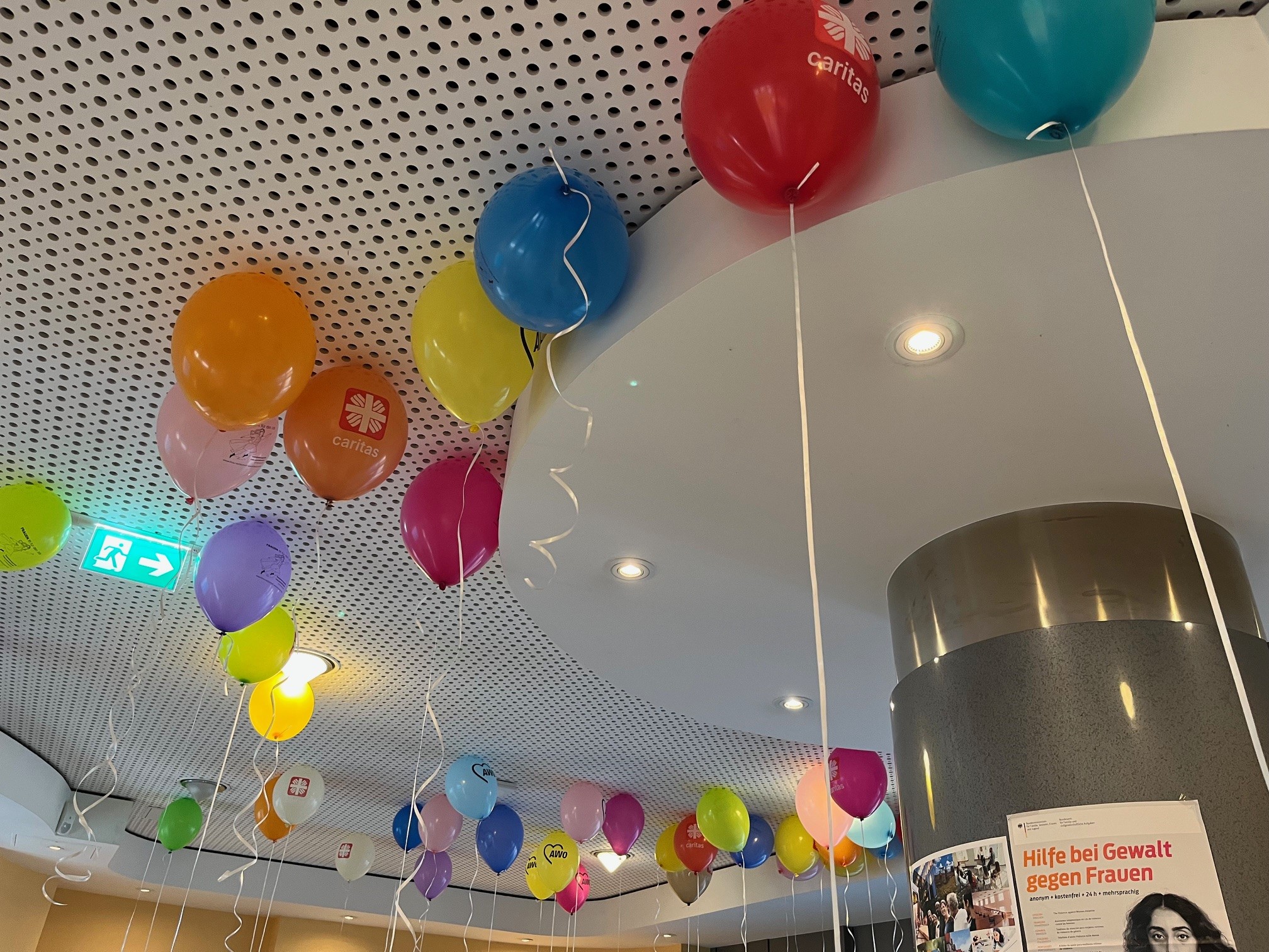 Bunte Luftballons schmücken das Foyer der VHS Schaumburg. An einer Säule hängt unter anderem ein Plakat mit Informationen zu Hilfe bei Gewalt gegen Frauen.