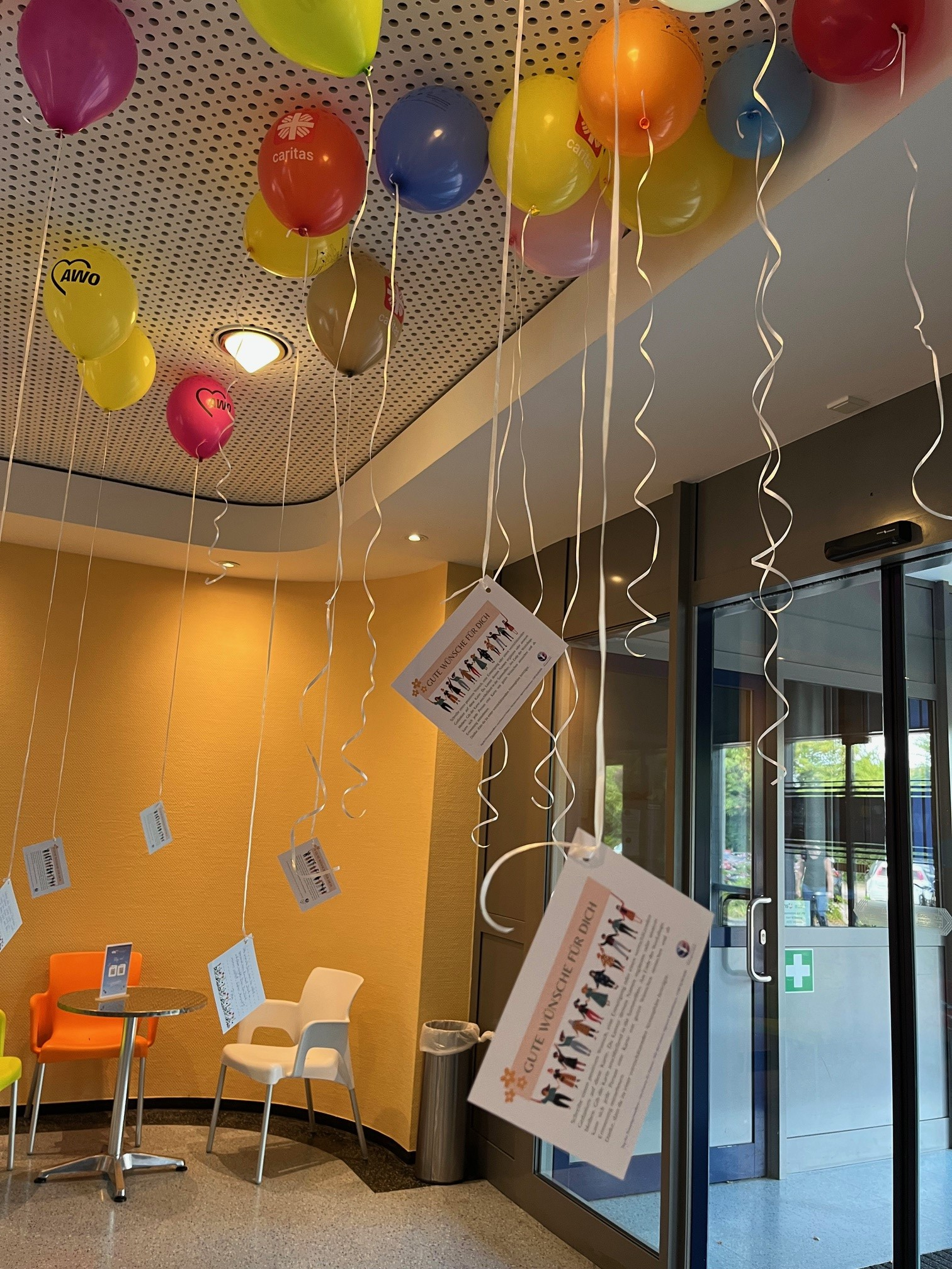 Bunte Luftballons mit angehängten Karten und guten Wünschen für Frauen schweben im Foyer der VHS Schaumburg.
